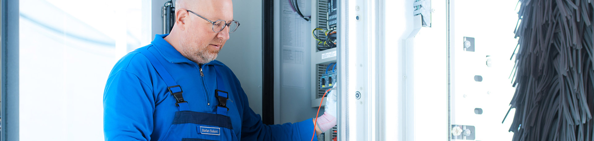 Eine Person arbeitet an einem Technikschrank einer Fahrzeugwaschanlage.